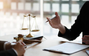 Business woman and lawyers discussing contract papers with brass scale on wooden desk in office. Law