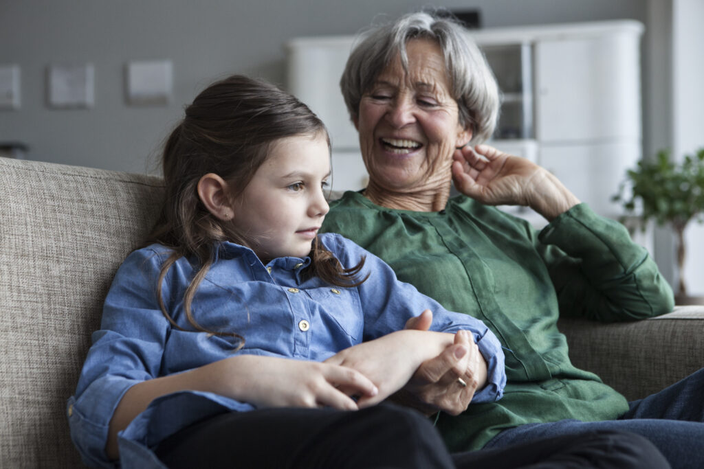 Grandmother and her granddaughter sitting together on the couch at home